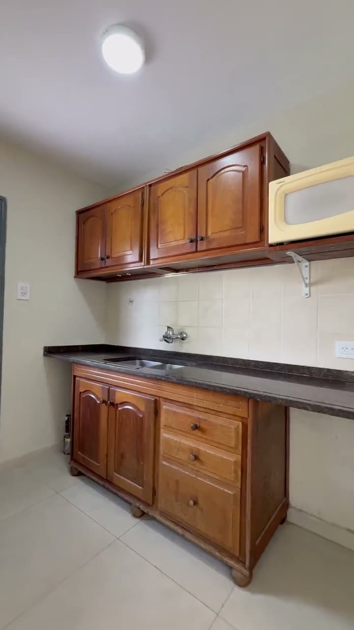 La cocina, con la mesada, la pileta, las alacenas de madera y el microondas