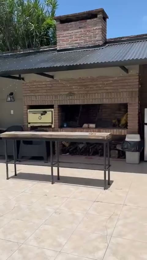 La parrilla de ladrillo y el horno pizzero, con la mesada de acero adelante